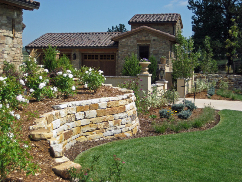 3-7' hand stacked Bulk Wall Stone was used to create a retaining wall outlining bushes with beautiful white flowers in the front yard of a residence in Colorado Springs, CO.